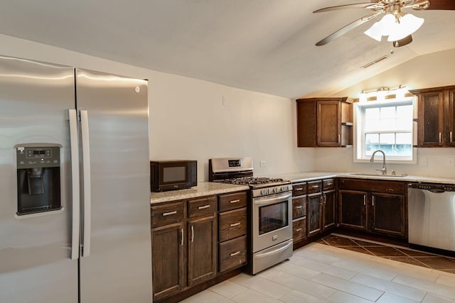 kitchen with vaulted ceiling, light tile patterned floors, appliances with stainless steel finishes, ceiling fan, and sink