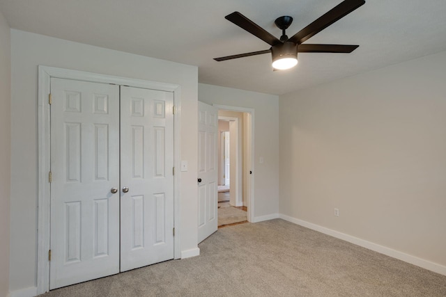 unfurnished bedroom featuring ceiling fan, a closet, and light carpet