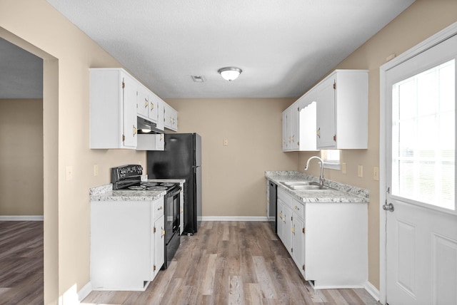 kitchen with black appliances, light hardwood / wood-style flooring, white cabinets, and sink