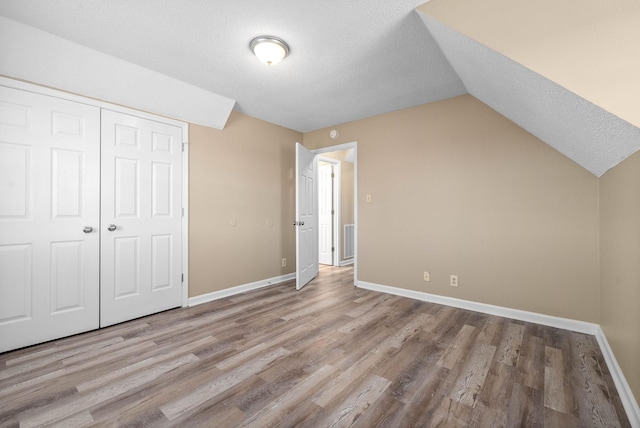 bonus room featuring a textured ceiling, vaulted ceiling, and light hardwood / wood-style flooring