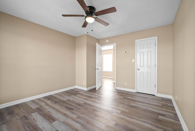 empty room featuring ceiling fan, a textured ceiling, and wood-type flooring