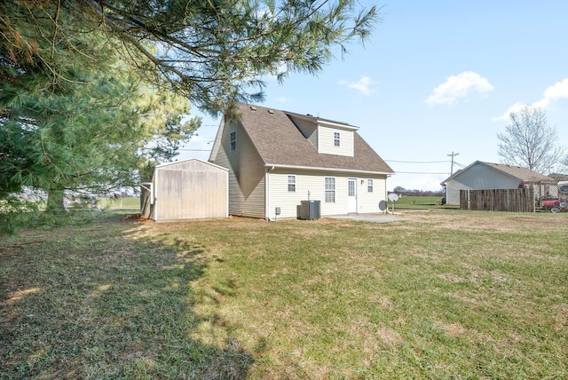 rear view of house with central air condition unit, a lawn, and a storage unit