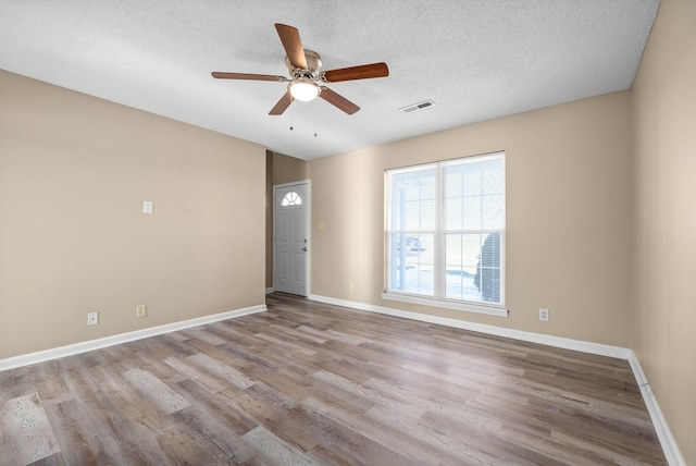 unfurnished room featuring light wood-type flooring, ceiling fan, and a textured ceiling