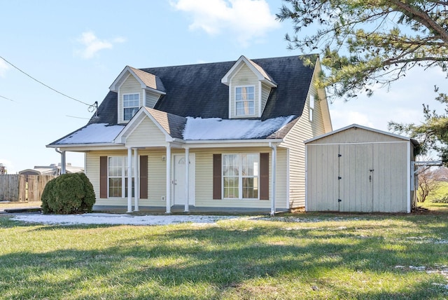 cape cod house featuring a front yard and a storage shed