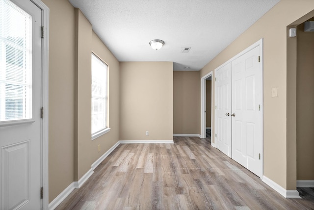 unfurnished bedroom with light wood-type flooring and a textured ceiling