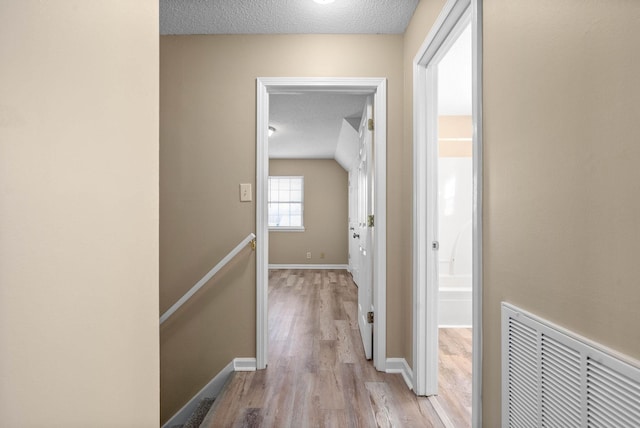 hall featuring a textured ceiling and light hardwood / wood-style flooring