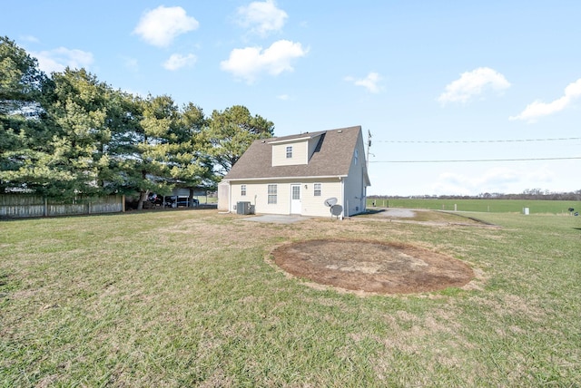 rear view of house with central AC unit and a lawn