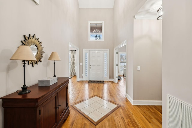 entrance foyer with a high ceiling, light wood-type flooring, and ornamental molding