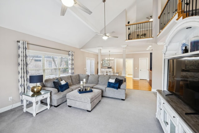 carpeted living room with high vaulted ceiling, a notable chandelier, decorative columns, and ornamental molding