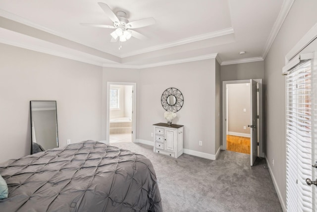 carpeted bedroom with ceiling fan, ornamental molding, ensuite bath, and a tray ceiling