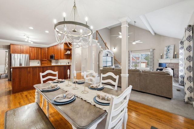 dining area with ornate columns, lofted ceiling, light wood-type flooring, crown molding, and ceiling fan with notable chandelier