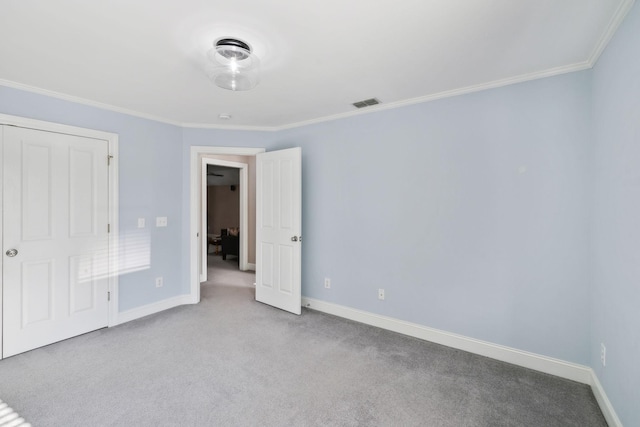 unfurnished bedroom with a closet, light carpet, and crown molding