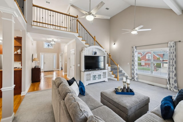 living room featuring a high ceiling, decorative columns, and light wood-type flooring