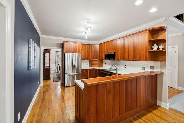 kitchen with stainless steel appliances, light wood-type flooring, crown molding, and kitchen peninsula