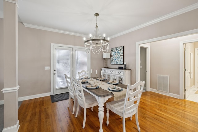 dining room with an inviting chandelier, hardwood / wood-style floors, and crown molding