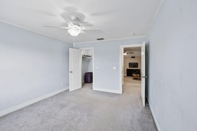 unfurnished bedroom with ceiling fan, light colored carpet, ornamental molding, and a closet