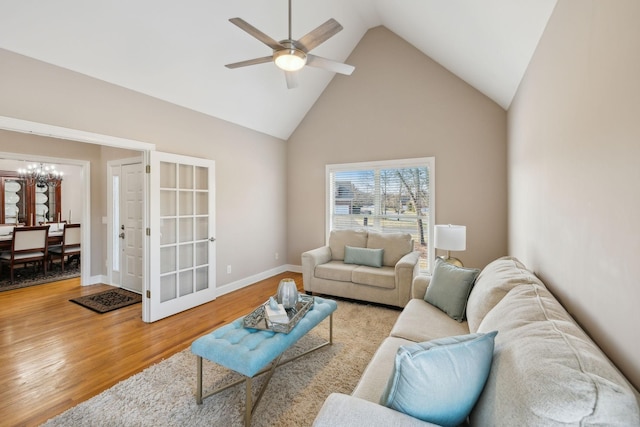 living room with ceiling fan with notable chandelier, high vaulted ceiling, and hardwood / wood-style flooring