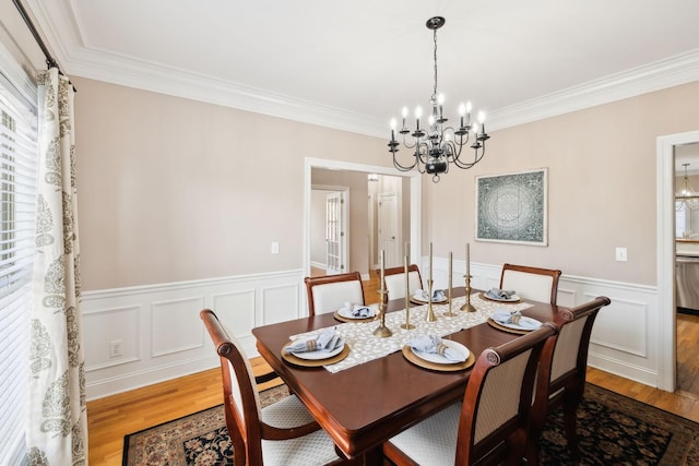 dining space featuring hardwood / wood-style floors, crown molding, and a chandelier