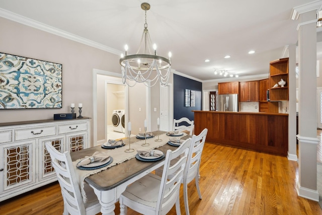 dining room featuring independent washer and dryer, crown molding, a chandelier, and light hardwood / wood-style flooring