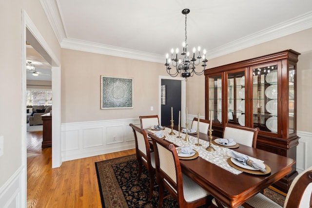 dining space with ornamental molding, a notable chandelier, and light hardwood / wood-style flooring