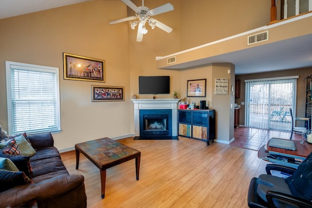 living room featuring ceiling fan, light hardwood / wood-style flooring, and a high ceiling