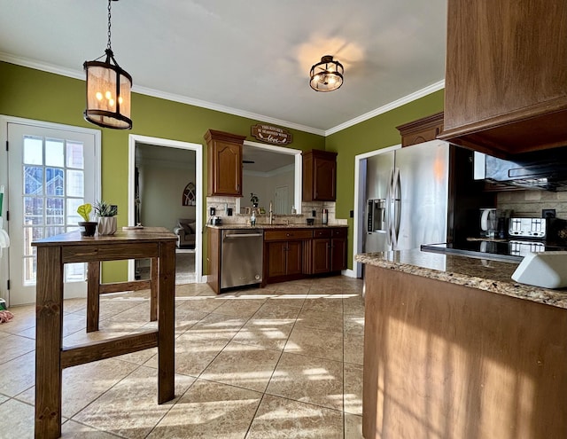 kitchen with appliances with stainless steel finishes, hanging light fixtures, crown molding, sink, and tasteful backsplash