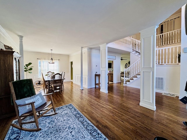 living area featuring ceiling fan with notable chandelier, decorative columns, ornamental molding, and dark hardwood / wood-style floors