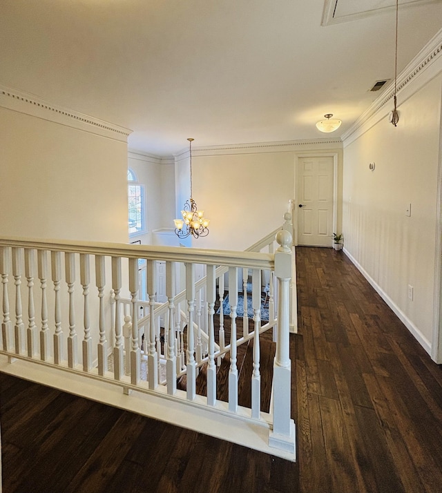 corridor with dark hardwood / wood-style flooring, ornamental molding, and a notable chandelier