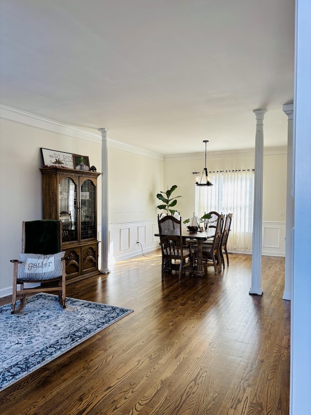 dining space featuring hardwood / wood-style flooring, crown molding, and ornate columns