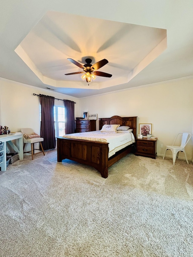 bedroom featuring ceiling fan, light colored carpet, and a tray ceiling