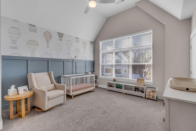 carpeted bedroom with ceiling fan, lofted ceiling, and a nursery area