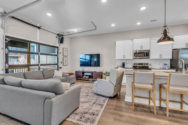 living room with light hardwood / wood-style floors and sink