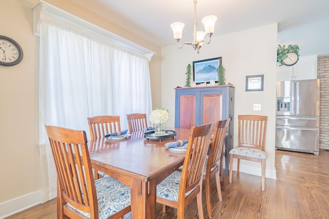 dining room with light wood-type flooring and an inviting chandelier