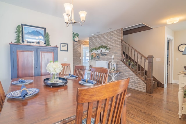 dining area featuring an inviting chandelier, brick wall, and hardwood / wood-style floors