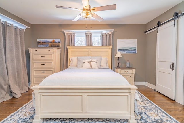 bedroom featuring ceiling fan, a barn door, and hardwood / wood-style floors