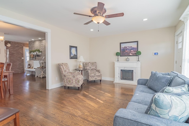 living room featuring ceiling fan, dark hardwood / wood-style flooring, and brick wall