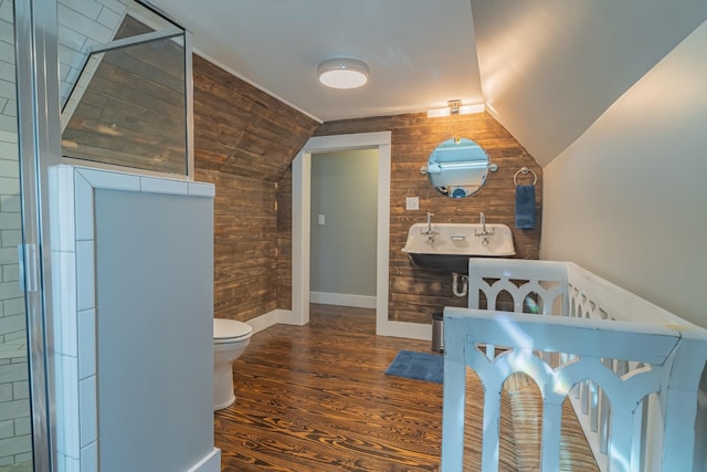 bathroom with lofted ceiling, wooden walls, sink, toilet, and hardwood / wood-style flooring