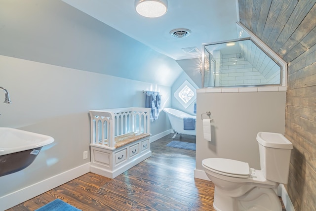 bathroom with a tub, wood-type flooring, toilet, and vaulted ceiling