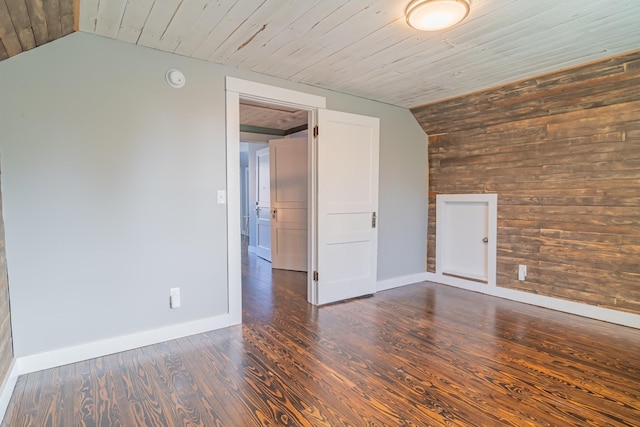 empty room featuring vaulted ceiling, wood ceiling, dark hardwood / wood-style flooring, and wood walls