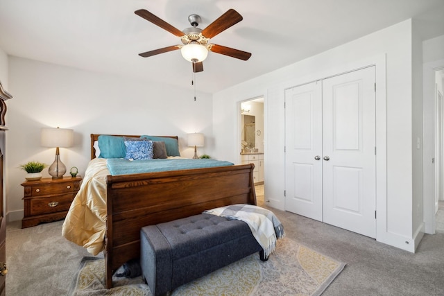 bedroom with ceiling fan, light colored carpet, a closet, and ensuite bath