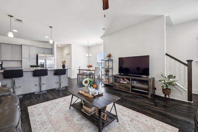 living room with ceiling fan with notable chandelier and dark hardwood / wood-style floors