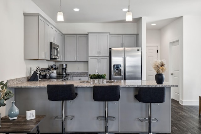 kitchen with appliances with stainless steel finishes, a kitchen breakfast bar, kitchen peninsula, and pendant lighting