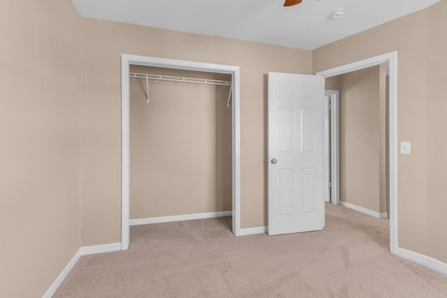 unfurnished bedroom featuring ceiling fan, a closet, and light carpet