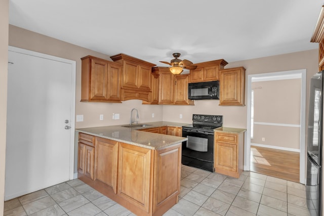 kitchen with kitchen peninsula, light stone countertops, black appliances, ceiling fan, and sink