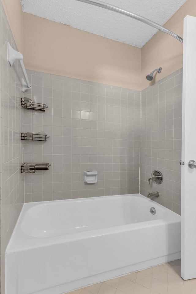 bathroom featuring a textured ceiling and tiled shower / bath