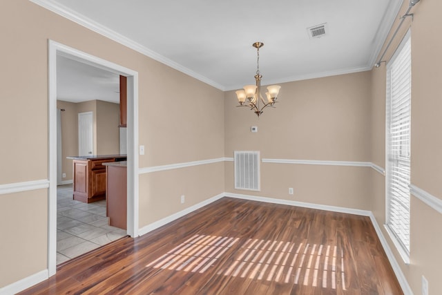 spare room featuring dark hardwood / wood-style flooring, crown molding, plenty of natural light, and a notable chandelier