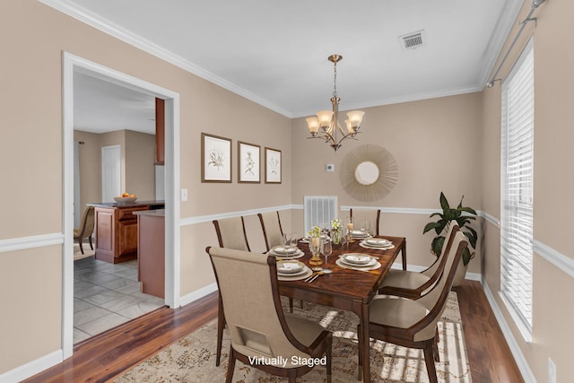 dining room featuring an inviting chandelier, crown molding, and light hardwood / wood-style flooring