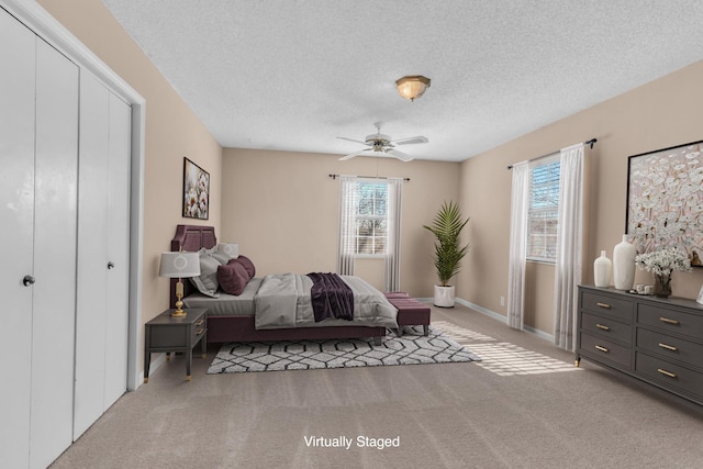 carpeted bedroom with a textured ceiling, ceiling fan, and multiple windows