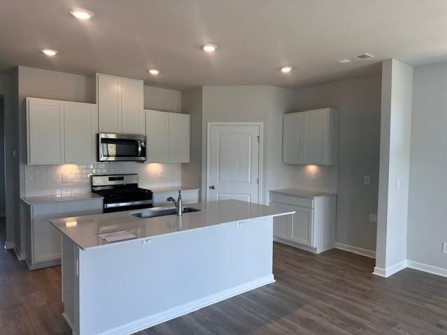 kitchen with appliances with stainless steel finishes, a kitchen island with sink, and white cabinetry