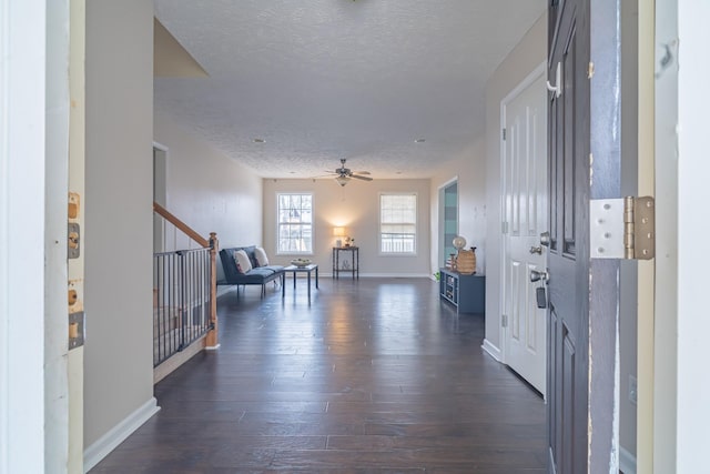 foyer entrance featuring ceiling fan, dark wood-type flooring, and a textured ceiling